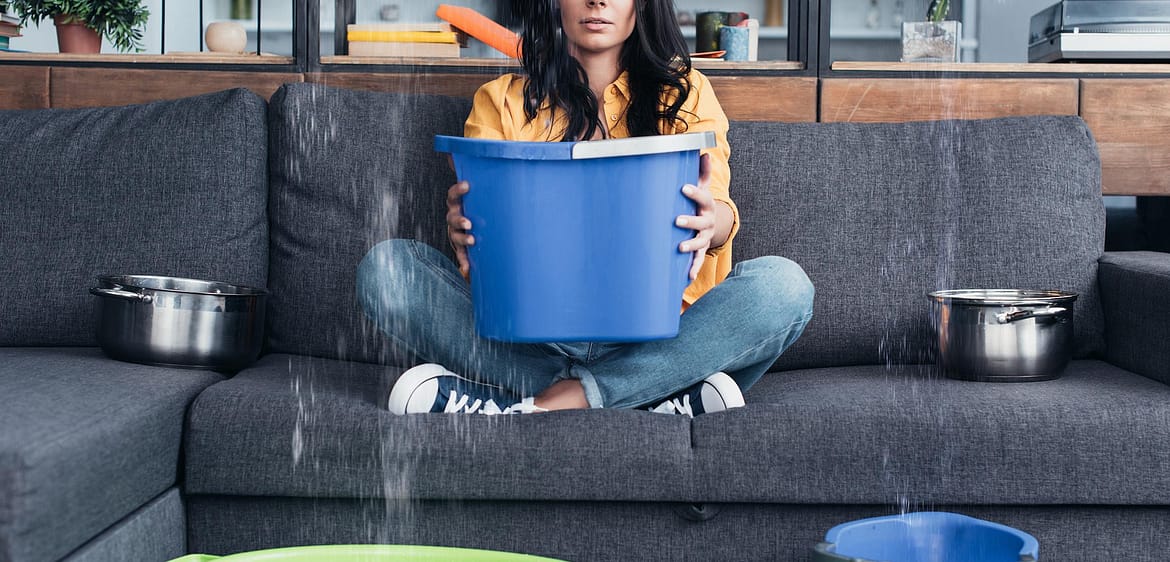 water-damage-aquadry | woman holding a bucket trying to catch water dripping