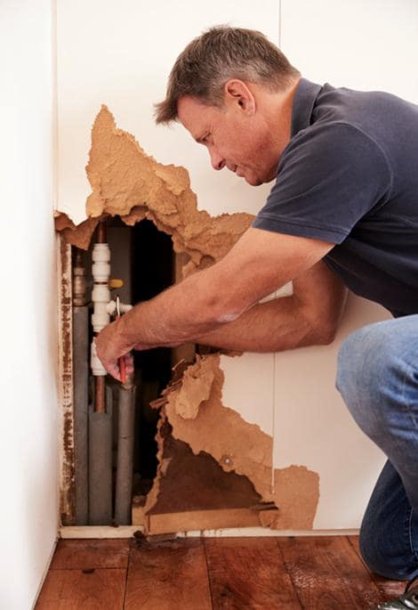 middle-aged-man-repairing-burst-water-pipe-vertical