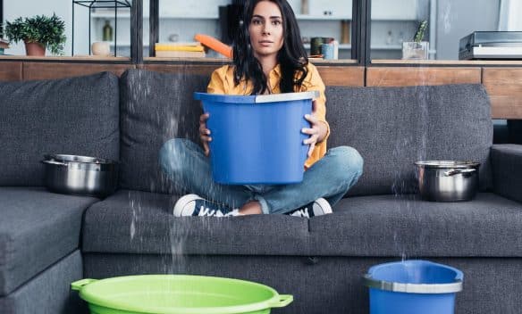 water-damage-aquadry | woman holding a bucket trying to catch water dripping