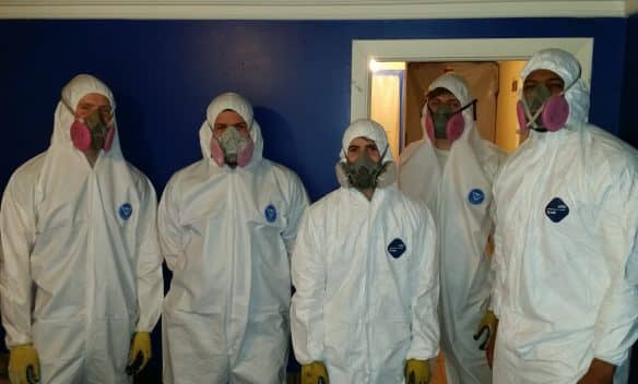 Mold Remediation Experts in Action - Five professionals wearing protective gear inspecting and treating mold-infested areas in a residential property. Their expertise ensures safe and effective mold removal.